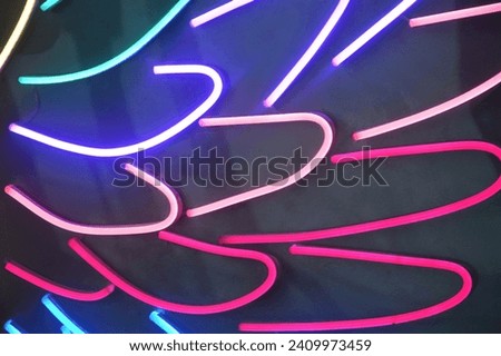 Colorful neon stripes, colored elements. Bright glowing curved lines on a black background. Abstract background.