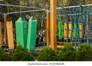 Colorful obstacle course with hanging cushions and net climbing area in outdoor adventure park. Physical challenge, sports entertainment, and outdoor activities - Powered by Shutterstock