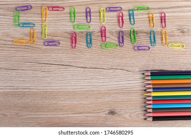 Colorful Office Paper Clips. Inscription School. Colored Pencil Crayons. Wooden School Bench Top.