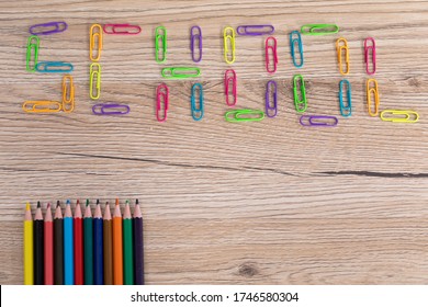 Colorful Office Paper Clips. Inscription School. Colored Pencil Crayons. Wooden School Bench Top.