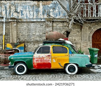 A colorful old car parked next to an old and messy wall. - Powered by Shutterstock