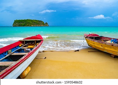 Colorful old wooden fishing boats docked by water on a beautiful beach coast land. White sand sea shore landscape on tropical Caribbean island. Holiday weekend/ summer vacation setting in Jamaica.