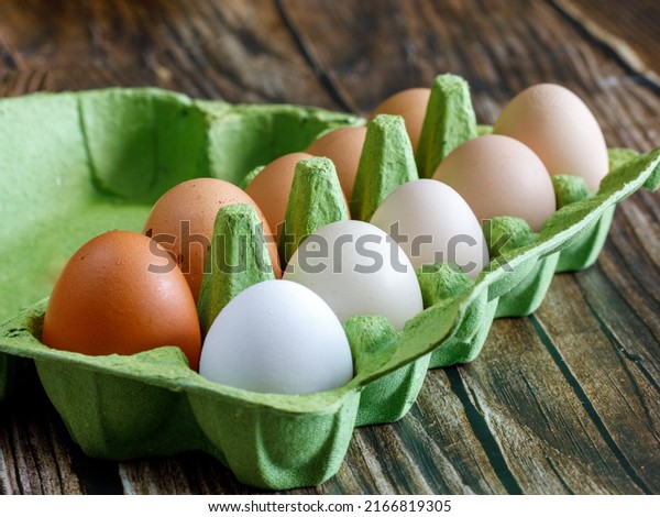 Colorful organic chicken eggs in green egg carton.\
These eggs were produced in small batches by a variety of chicken\
species so they appeared in different colors, patterns, and sizes.\
Side view