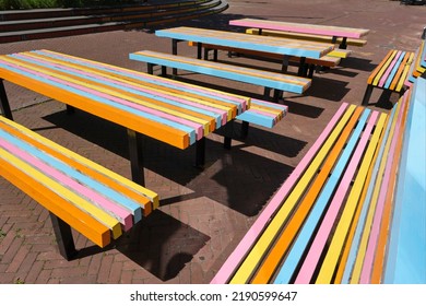 Colorful Outdoor Tables And Benches On A Terrace Of A Cafe Or Restaurant In The City In The Summer. Outdoor Furniture Painted In Orange, Yellow, Pink And Blue.