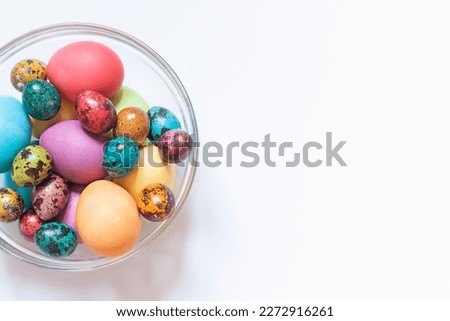 Colorful painted Easter eggs in the glass bowl on the white background. Close up. Copy space
