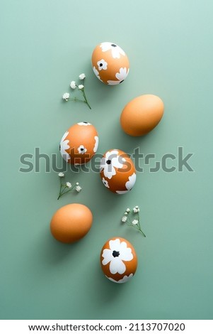 Colorful painted Easter eggs on green background with gypsophila. Elegant Easter flat lay composition