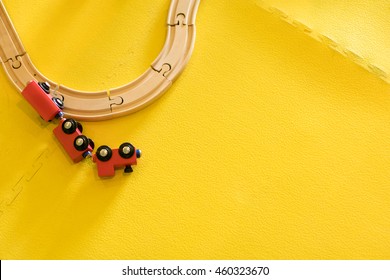 Colorful Painted Red Wooden Train Toy Wreck, Off The Wooden Track On A Yellow Floor Tile Background.