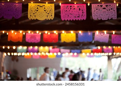 Colorful papel picado banners under festive lights at an event." - Powered by Shutterstock