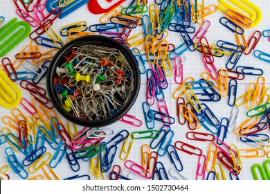 Colorful paperclips and fastener on the white,checked surface,top view