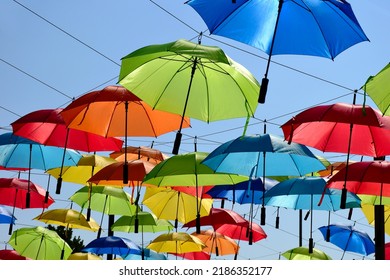 Colorful Parasol Sun Protection. Bright Umbrellas Suspended Overhead On Metal Wires. Climate Change And Global Warming Concept. Summer Travel Tourism And Vacation Theme. Design And Urban Environment. 