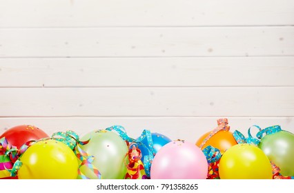 Colorful party background with copy space over white wooden boards and a border of colorful balloons and streamers - Shutterstock ID 791358265