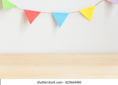 Colorful Party Flag On White Wall With Wood Table