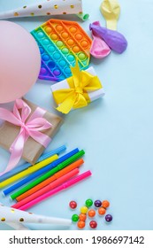 Colorful Party Invitation Background With Presents, Color Markers, Pop It Toy And Balloons. Vertical Image