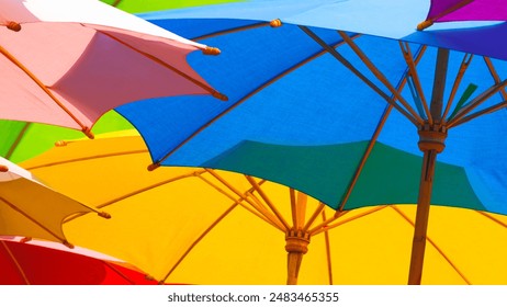 Colorful pattern background of outdoors wooden parasols with sunlight and shadow on surface, low angle view and selective focus - Powered by Shutterstock