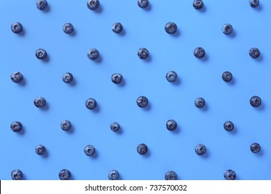 Colorful pattern of blueberries on blue background. From top view
