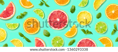 Colorful pattern of citrus fruit slices and mint leaves on blue background. Top view, flat lay