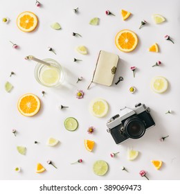 Colorful pattern made of orange, lemon, lime and flowers with lemonade and vintage camera and notebook.