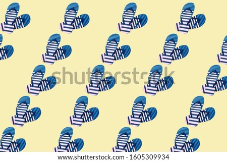 Colorful pattern of striped print flip flops isolated on trendy yellow background. Summer minimalism. Top view. Flat lay