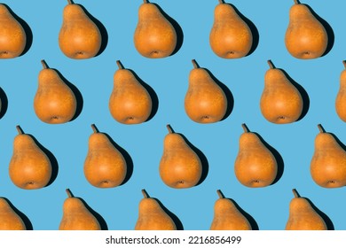 Colorful pear pattern. Yellow and orange Bera pears on a blue background. Ripe juicy fruits top view. Food background. Creative concept.