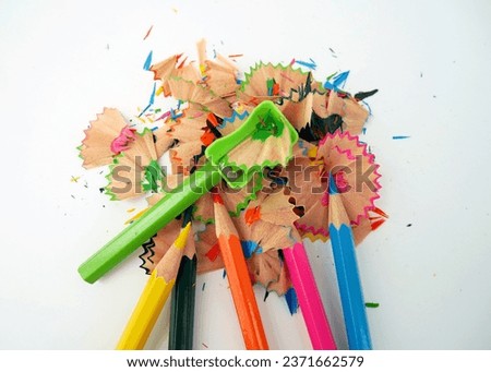 Colorful pencil shavings with pencils and green shavings on a white background. Whole and broken lead pencils on white background. The rest of the pencil. Macro, pile of shavings