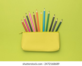 Colorful Pencils Arranged in Yellow Pencil Case Against Green Background - Powered by Shutterstock