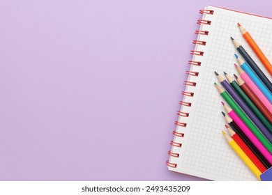 Colorful Pencils on Spiral Notebook with Grid Paper on a Purple Background - Powered by Shutterstock