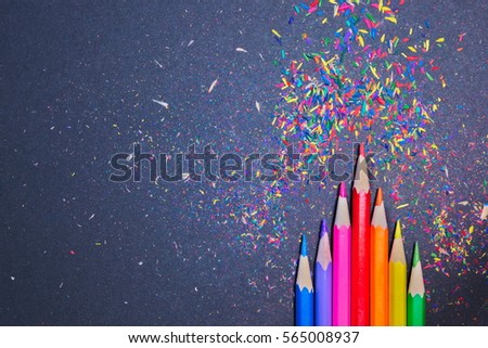 Colorful pencils with colorful shavings on a black background