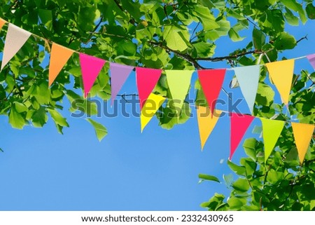 Colorful pennant string decoration against a tree and the summer sky