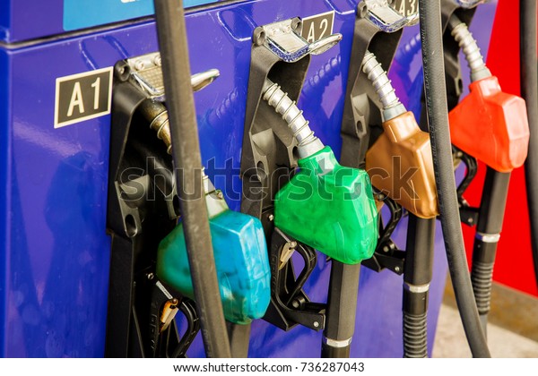 Colorful Petrol pump filling nozzles\
isolated on white background , Gas station in a service in warm\
sunset.Head fuel vehicle refueling facility in\
asia
