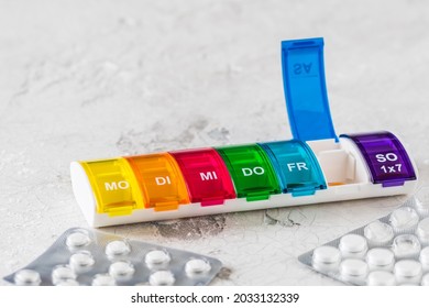 Colorful Pill Box For Weekly Dosing On A White Background, Abbreviations For Days Of The Week In German