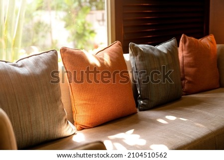 colorful  pillow cushion arrange on sofa bed bench booth window side with background of wooden blind shade in  morning day light from outside,home interior design background home sweet home concept