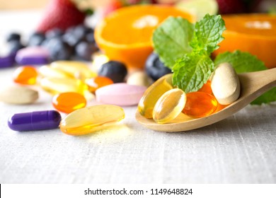 Farbige Pillen und Kapseln in Holzlöffel mit frischen Früchten.Vitamine und Ergänzung aus dem Obstkonzept.