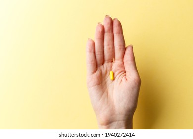 Farbige Tabletten und Tabletten in der Frau Hand auf buntem gelbem Hintergrund. Draufsicht. Flat lay. Kopiert Platz. Medizinkonzept. Minimalistisches abstraktes Konzept. Gelbe Arzneimittelkapsel