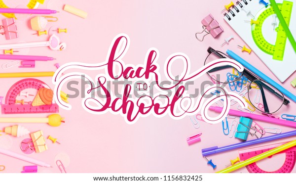 Colorful pink background with various School\
accessories are laid out in the form of a rainbow.  Flat lay top\
view. Study arrangement, making wish list or plans. Back to school\
letterig text.