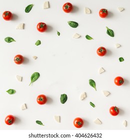 Colorful pizza ingredients pattern made of cherry tomatoes, basil and cheese on white background. Cooking concept.