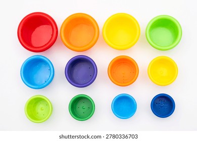 Colorful plastic nesting buckets and stacking cups for toddlers, vibrant educational toy set for early development of motor skills and logic, isolated on clean white background studio shot.