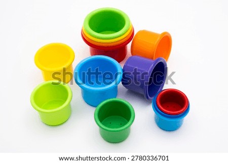 Colorful plastic nesting buckets and stacking cups for toddlers, vibrant educational toy set for early development of motor skills and logic, isolated on clean white background studio shot.