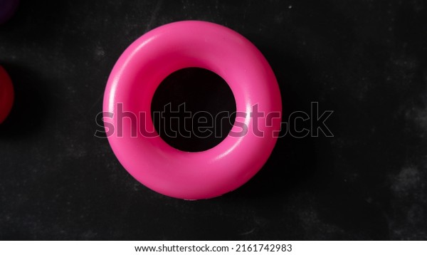 Colorful plastic ring isolated on\
wooden black background as illustration of swim ring. Swim\
Ring