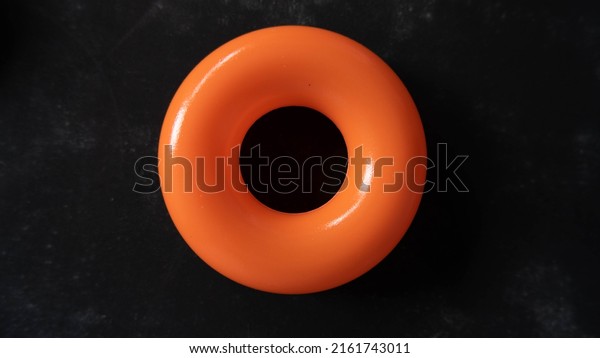 Colorful plastic ring isolated on wooden black\
background as illustration of swim\
ring