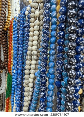 Colorful plastic rosaries close up shot in the market. Beautiful Muslim prayer beads close up view. Colorful chaplets for prayers. Religious beads with colorful strings. Plastic rosary market view.