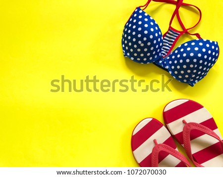 Colorful polka dot swimsuit with red & white striped sandal on yellow background.Accessories for summer.The concept of summertime,vacation,swimming activity,lifestyle.Copy space.Selective focus.