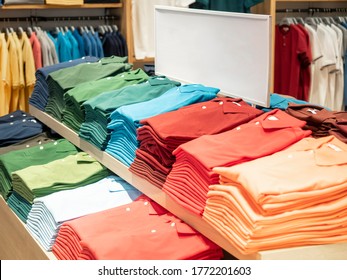 Colorful Polo T Shirt Stack On Shelf In Large Department Store Shop. Copy Space On White Sign Board.