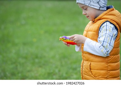 Colorful Popular Fidget Toy Using For Development Of Fine Motor Skills And Mental Health. Kid Playing With Popit Rainbow Toy Trend Of 2021 Year From Tik Tok. Anti Stress Toy For Children With Special