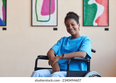 Colorful portrait of black teenage girl with disability smiling at camera while visiting modern art gallery or museum, copy space - Powered by Shutterstock