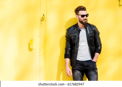 Colorful portrait of a handsome man dressed in white t-shirt, jacket and jeans on the yellow background