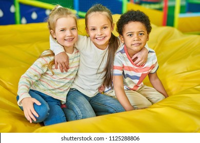 Colorful portrait of three cute children smiling happily looking at camera while having fun in children play center, copy space - Shutterstock ID 1125288806