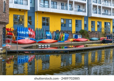 Colorful recreational sports kayaks on a dock in front of a building in the residential district of Maida Vale in London on the Regent's Canal with the water reflecting everything. - Powered by Shutterstock