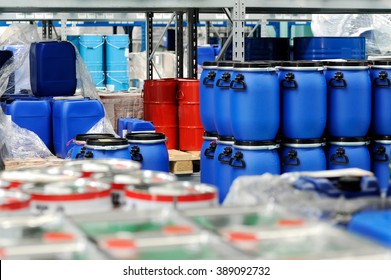 Colorful red metal and blue plastic barrels or drums stored in a warehouse stacked on top of one another for retail packaging for industrial supplies - Powered by Shutterstock