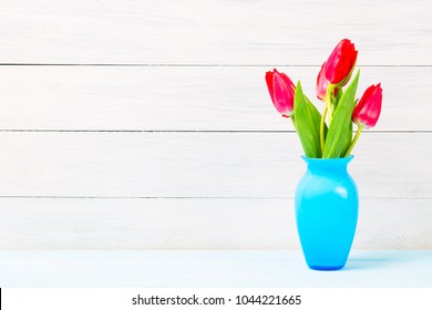 Colorful Red Spring Tulip Flowers In Nice Blue Vase On Light Wooden Background As Greeting Card. Mothersday Or Spring Concept