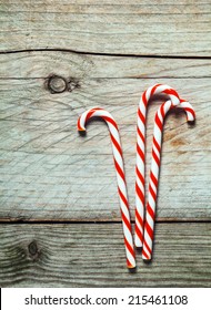 Colorful red and white striped Xmas candy canes on a rustic wooden background with copyspace for your seasonal Christmas greeting or invitation
